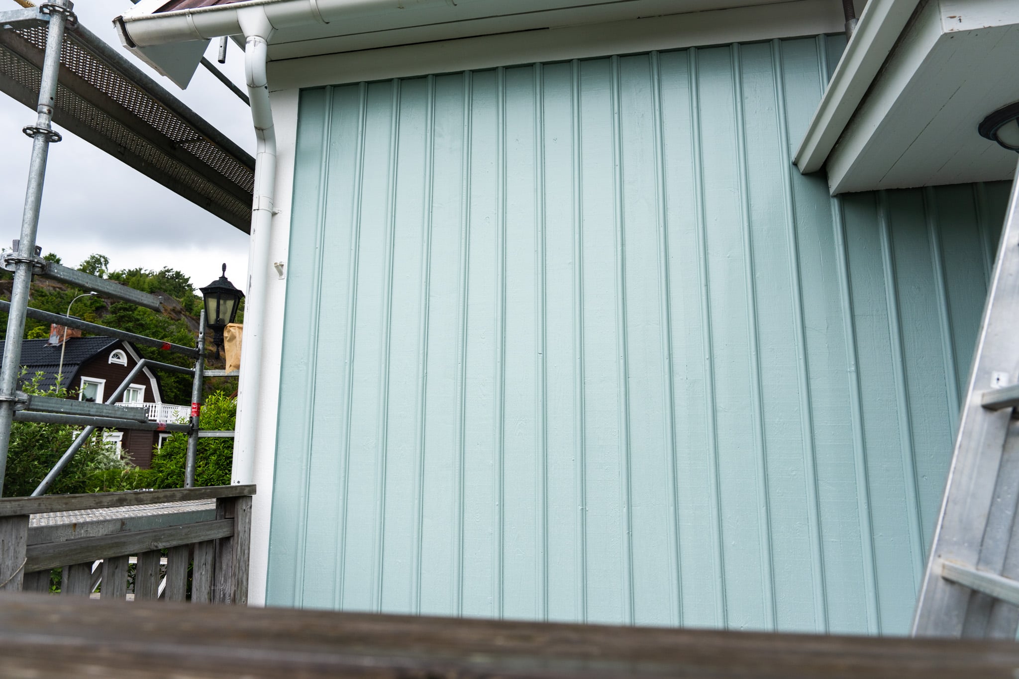 Nymålad stående träpanel i ljusgrönt efter fasadrenovering